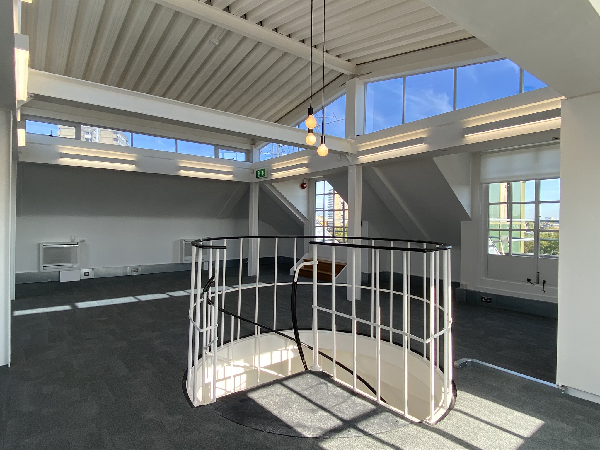 Empty top floor room with tall window features and stairwell